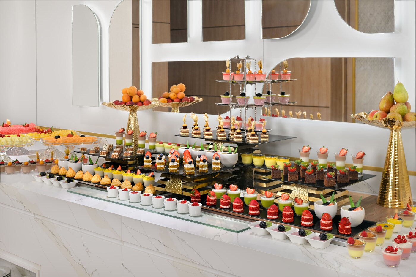 H-Gourmet dessert buffet with assorted cakes, fruit tarts, and layered desserts