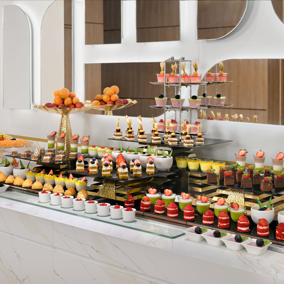 Lavish H-Gourmet dessert buffet with assorted cakes, fruit tarts, and layered desserts