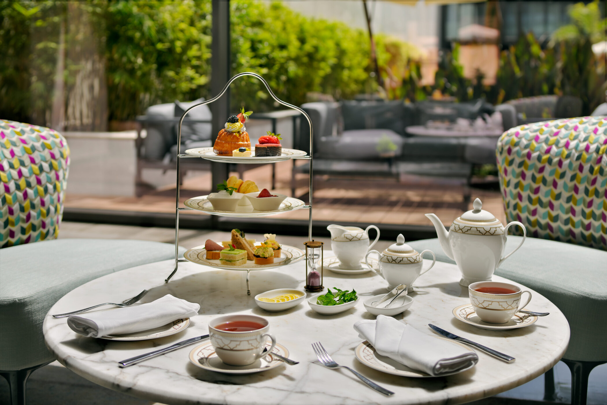 Outdoor afternoon tea service with a tiered stand, teapot, and fine china by H-Gourmet